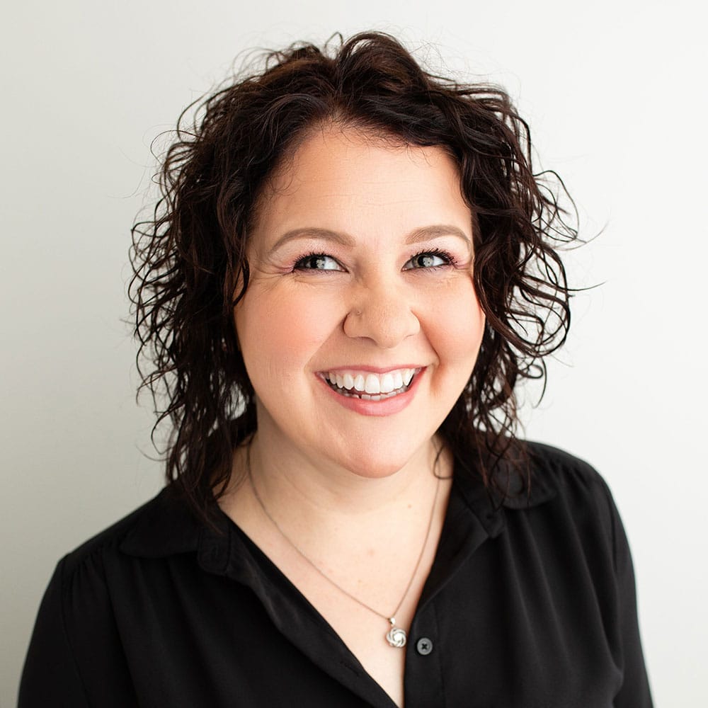 Kristin Financial Coordinator for Cardall Orthodontics; middle-aged woman with black curly hair wearing black scrubs