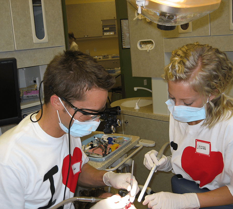 Dr Cardall working as dentist at charity event with Lindsey assisting him